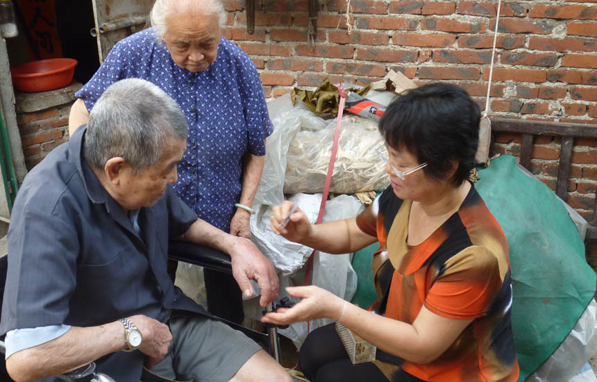 杨大姐为坐轮椅的老人陈伯坤蜂疗